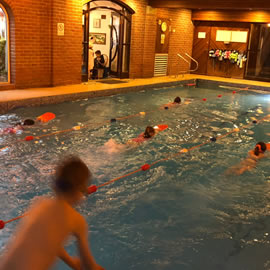 Childrens classes 10 metres and above, teacher on poolside.